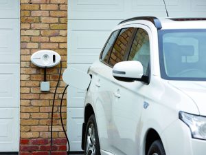 Mitsubishi Outlander PHEV charging on tethered wall mounted white home charge unit